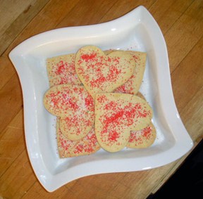 heart shaped cookies with red sprinkles on a white plate