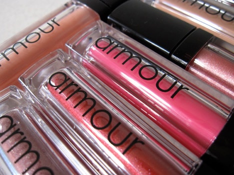 Armour Beauty lip glosses in various shades on a white counter