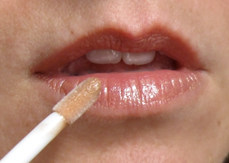 fair skinned woman applying lip gloss
