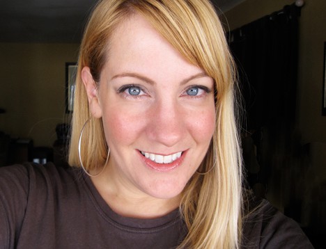 A blonde woman smiling wearing makeup