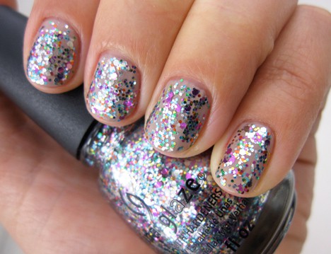 A hand holding a China Glaze nail polish with a confetti glitter explosion nail polish