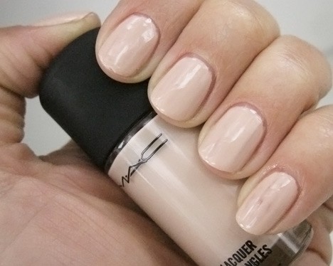 a hand with a milky light nude polish holding a nail lacquer