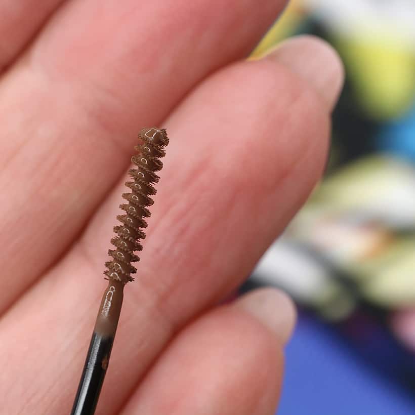Close up picture of Urban Decay Brow Endowed brush with a hand in the background