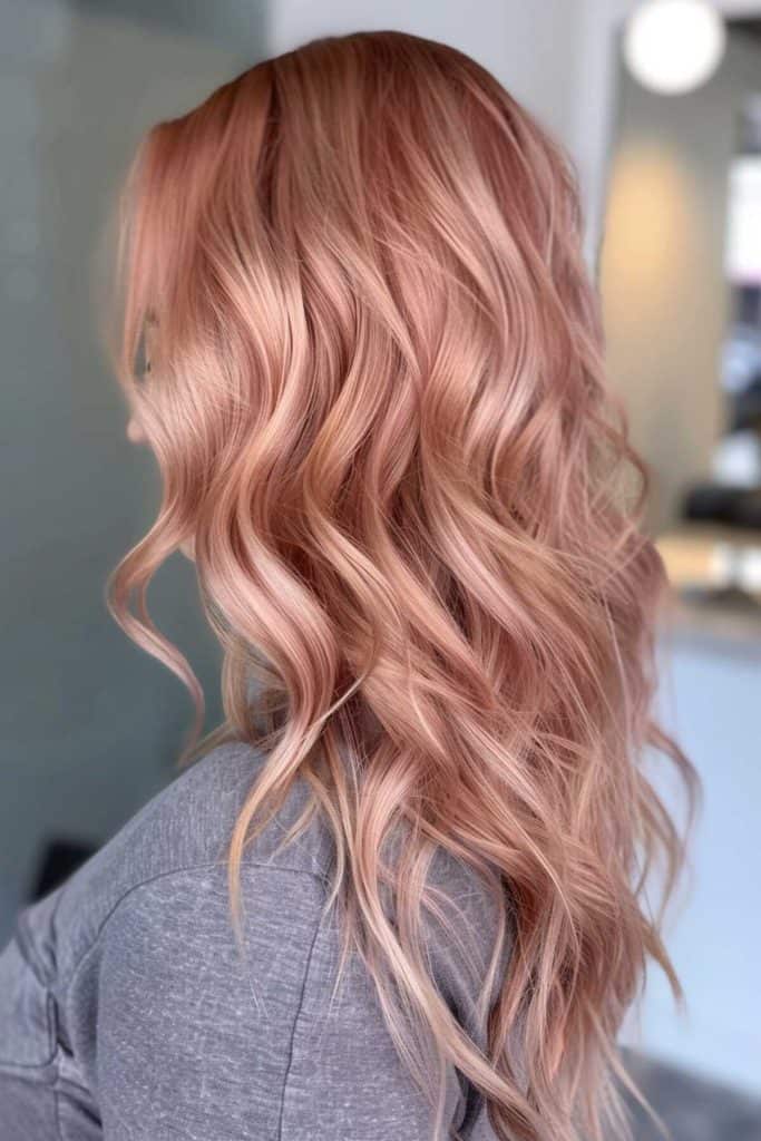 Woman with long, wavy rose gold hair viewed from behind.