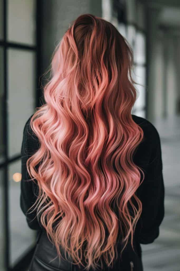 A woman with long, wavy rose gold hair standing in a corridor, viewed from behind.