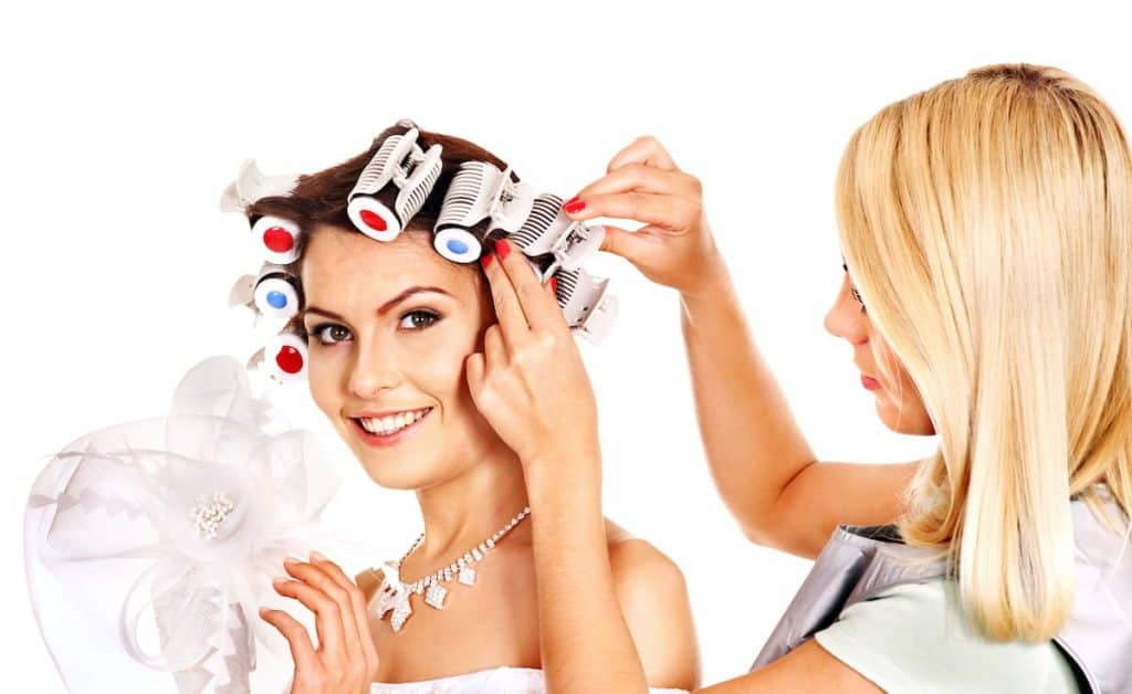 A brunette woman having hot rollers put in her in short hair