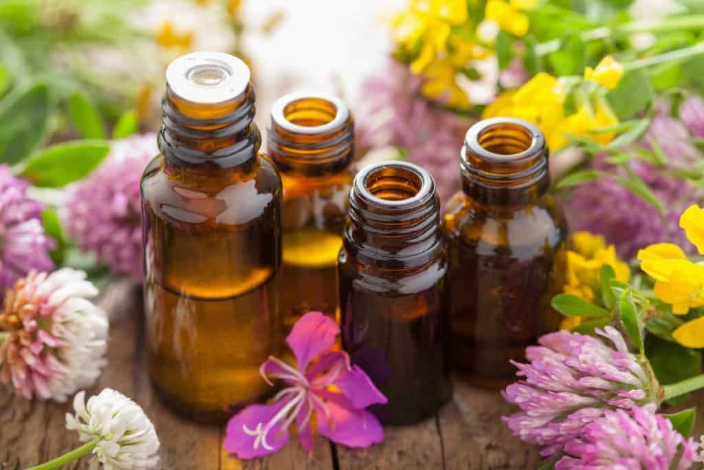 essential oil bottles on a wood table surrounded by flowers