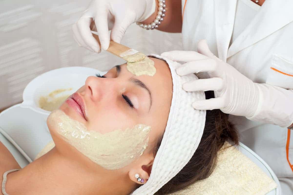 woman having a face mask applied while getting a facial