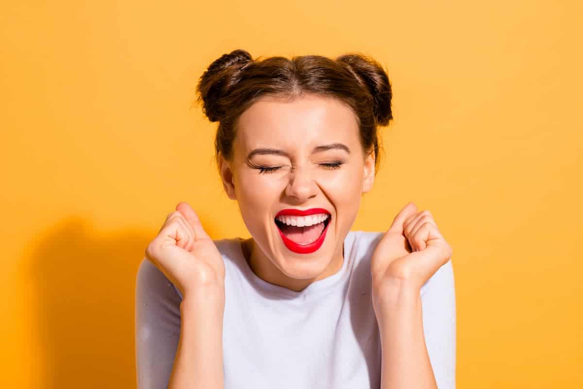 Happy woman with space buns hairstyle with a orange background