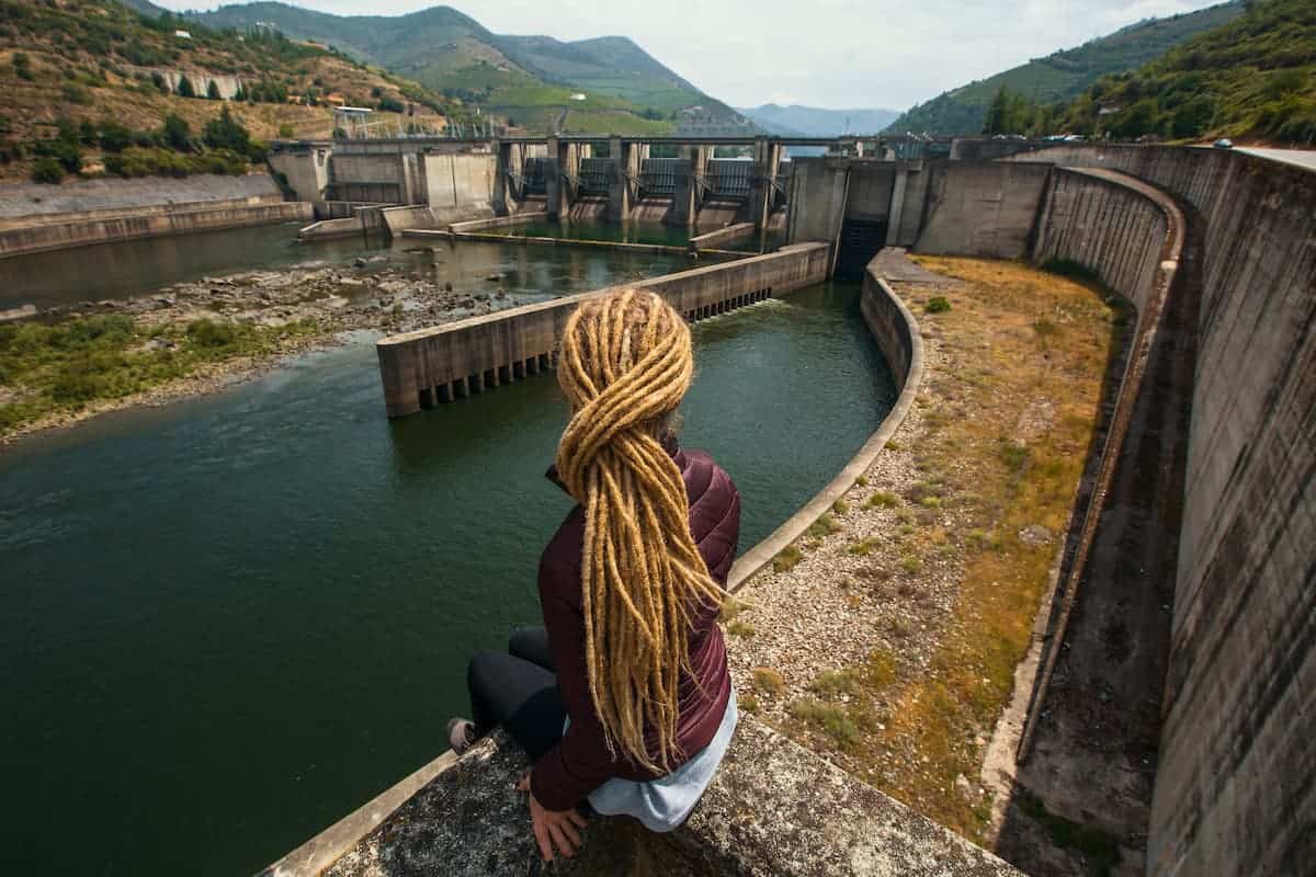 woman with long dreadlocks sitting looking at old structure