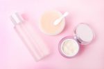 pink background with cleansing balm and other skincare products in clear containers