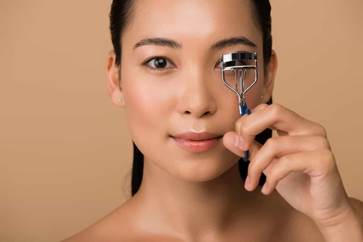 asian woman holding an eyelash curler