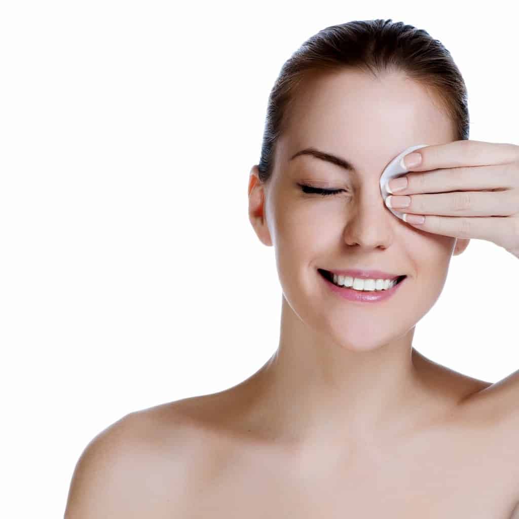 Woman with eye makeup cleanser on a cotton pad wiping eye