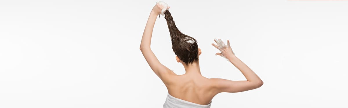 Woman on a white background washing her hair with shampoo
