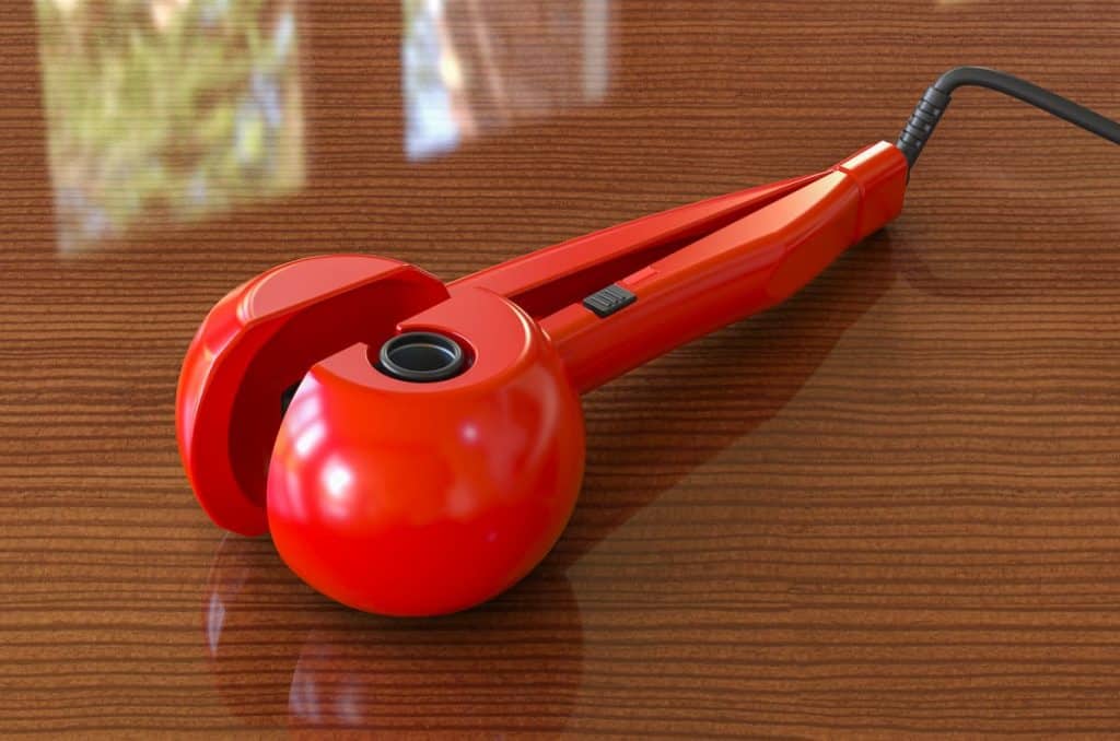 red automatic hair curler machine on a wood table