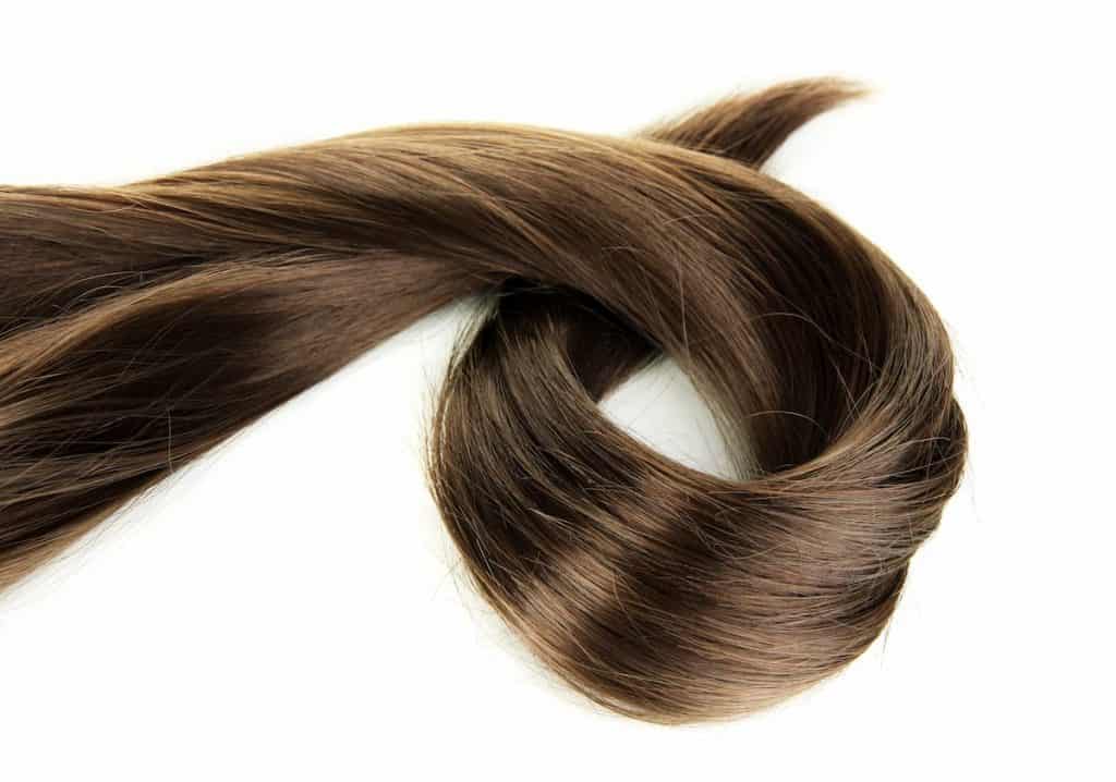 a lock of ash brown hair looped on a table with a white background