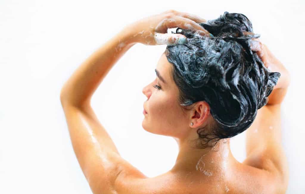 Woman with black colored hair shampooing her hair