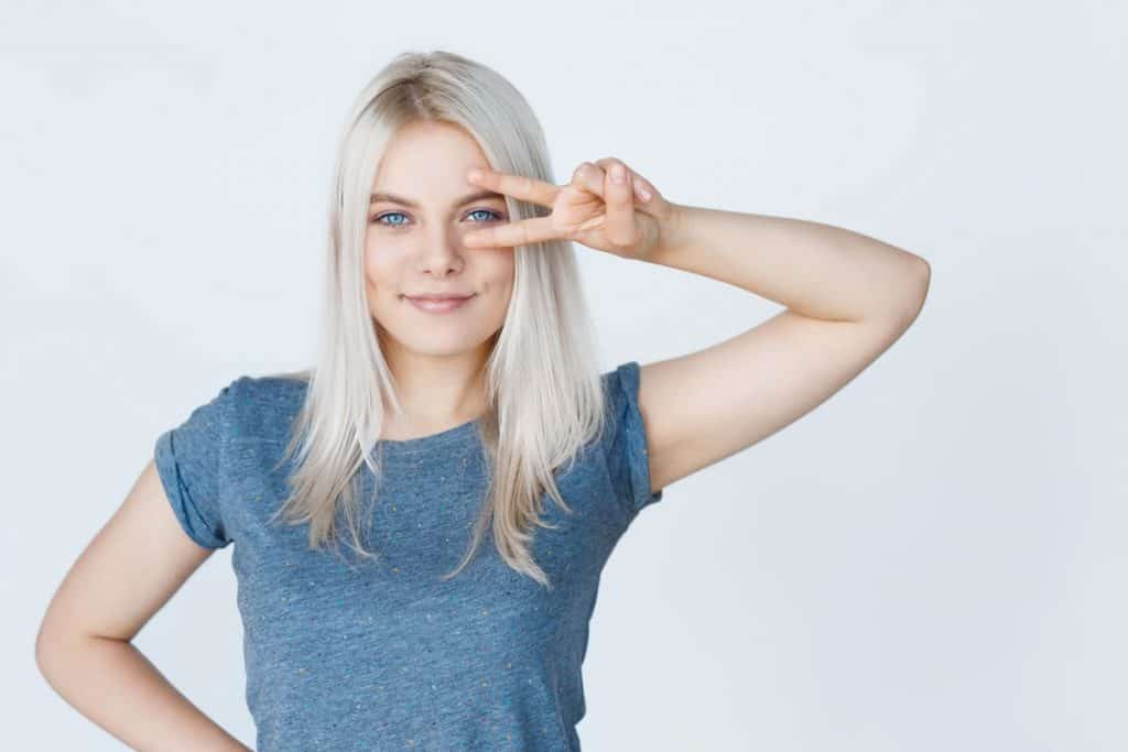 Young woman with bleached hair doing a peace sign