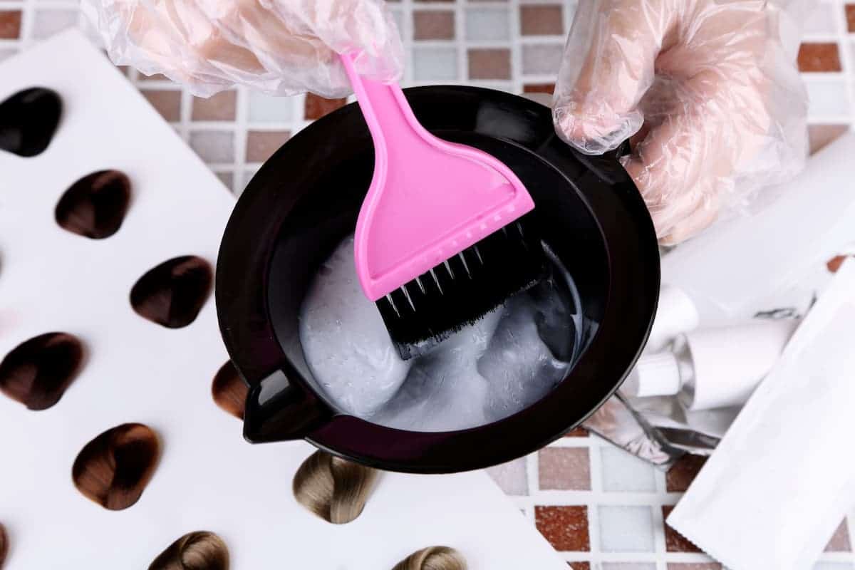 hair dye in a black bowl with pink brush and mixed hair color samples