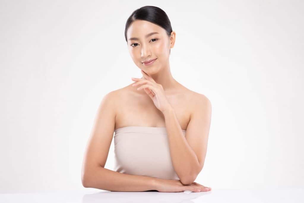 beautiful asian young woman touching cheek smiling with clean and fresh skin