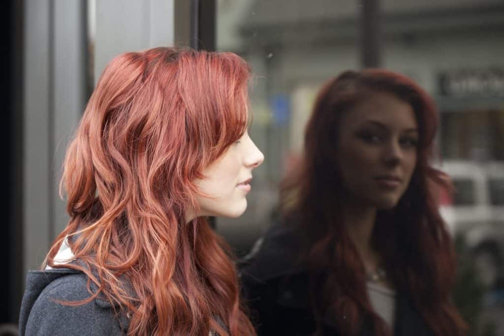 young woman with beautiful auburn hair looking at a tempered glass of building