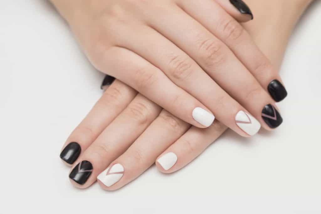 hands folded on top of each other with black and white press on nails