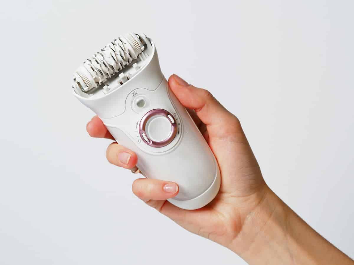 woman's hand holding a white epilator