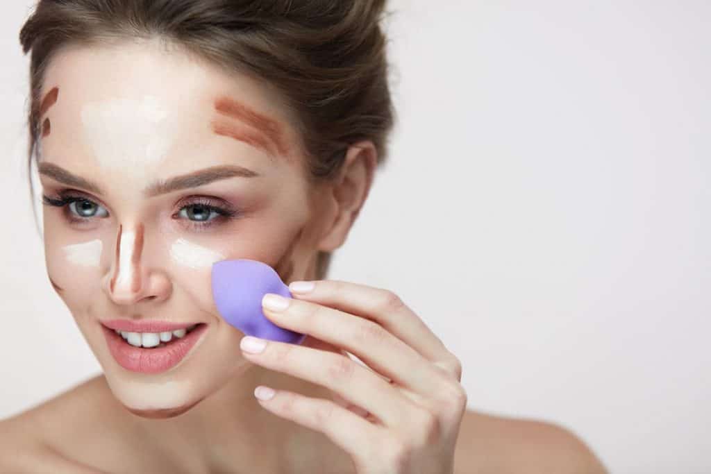 Beautiful female applying makeup with sponge