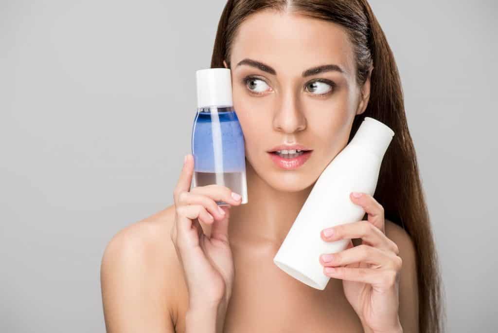 Beautiful girl with perfect skin holding two bottles with makeup remover