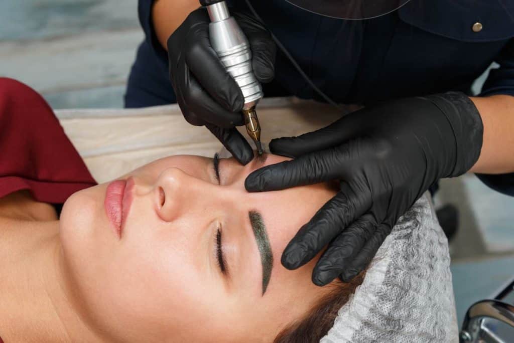 brow technician using nanoblade on female client's eyebros