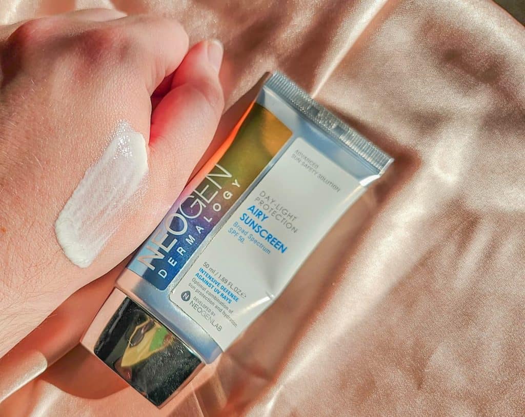 A tube of neogen airy sunscreen and a person's hand with a swatch of the sunscreen