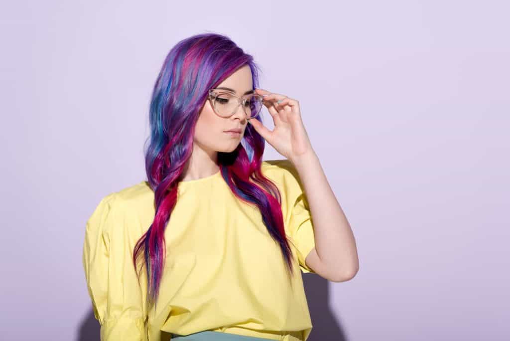 young woman with colorful hair and stylish eyeglasses on pink