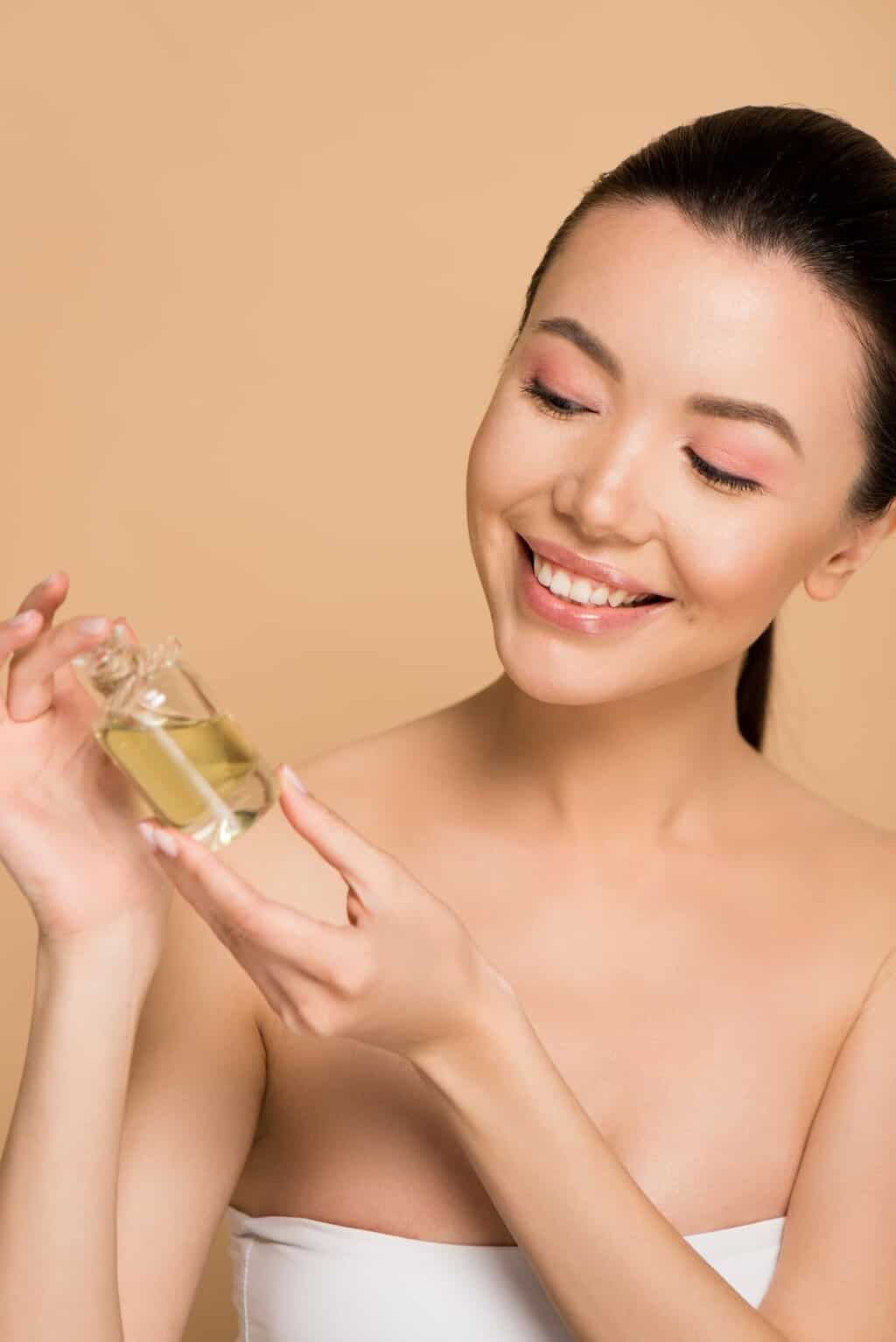 Asian woman holding a bottle of serum isolated in a beige background