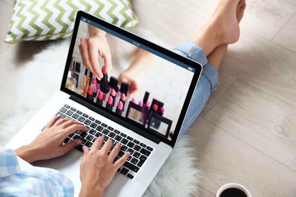 woman using laptop on her lap watching cosmetics photo