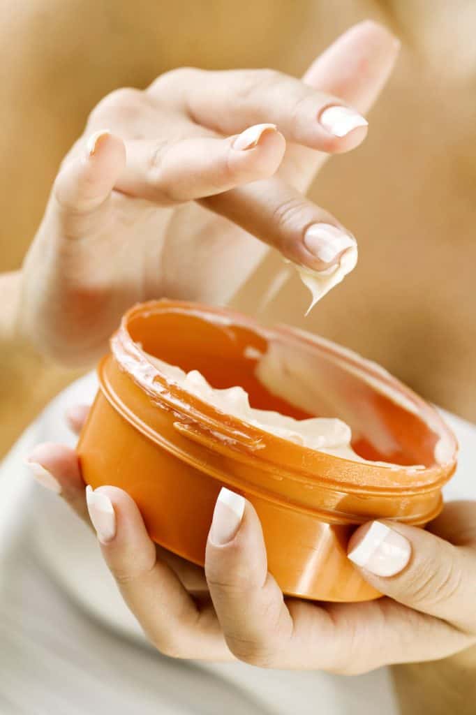 closeup view of woman's hand getting body butter from container