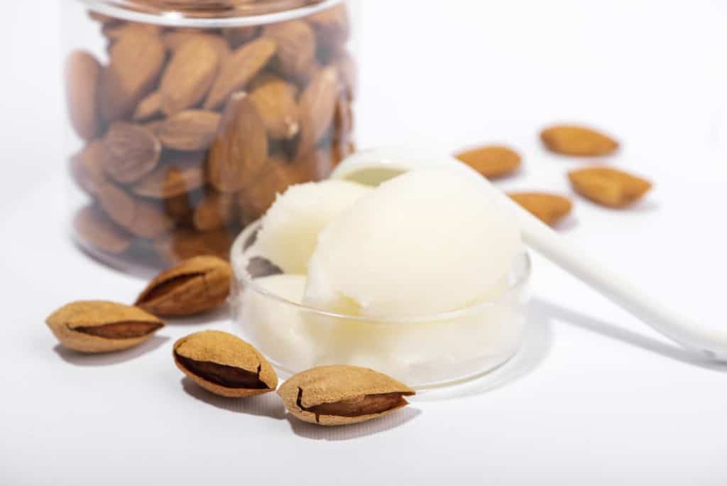 sweet almond body butter and natural almonds on white background