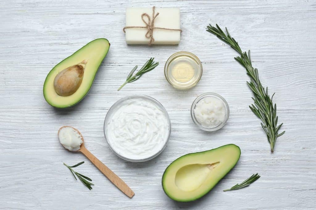 beautiful composition with half-sliced avocados and avocado body butter