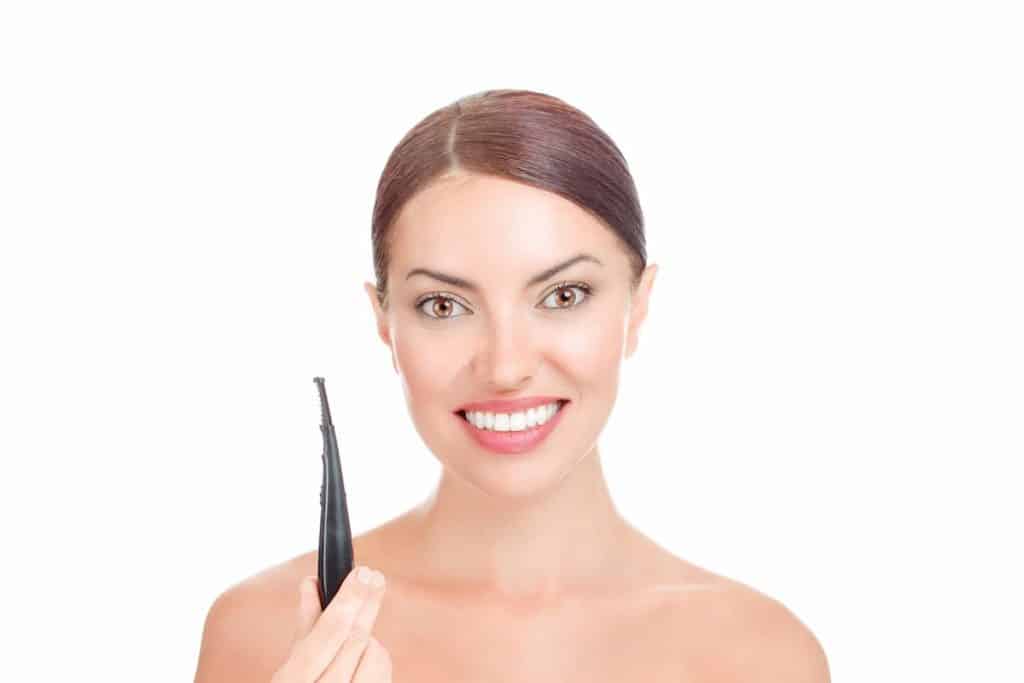 beautiful woman holding heated electric eyelash curler pen smiling