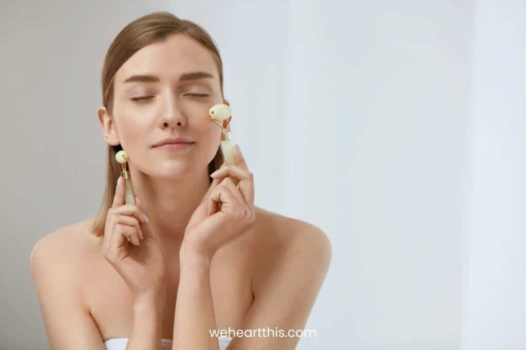a girl massaging her own face with two clear quartz roller