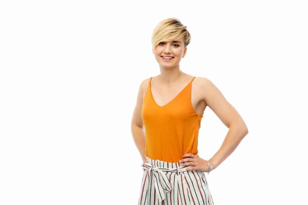 a young lady wearing mustard top with karen haircut is posing at the camera