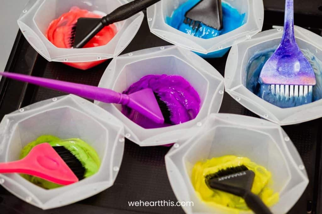 six different mixing bowls with neon color korean hair dyes laid at a black table