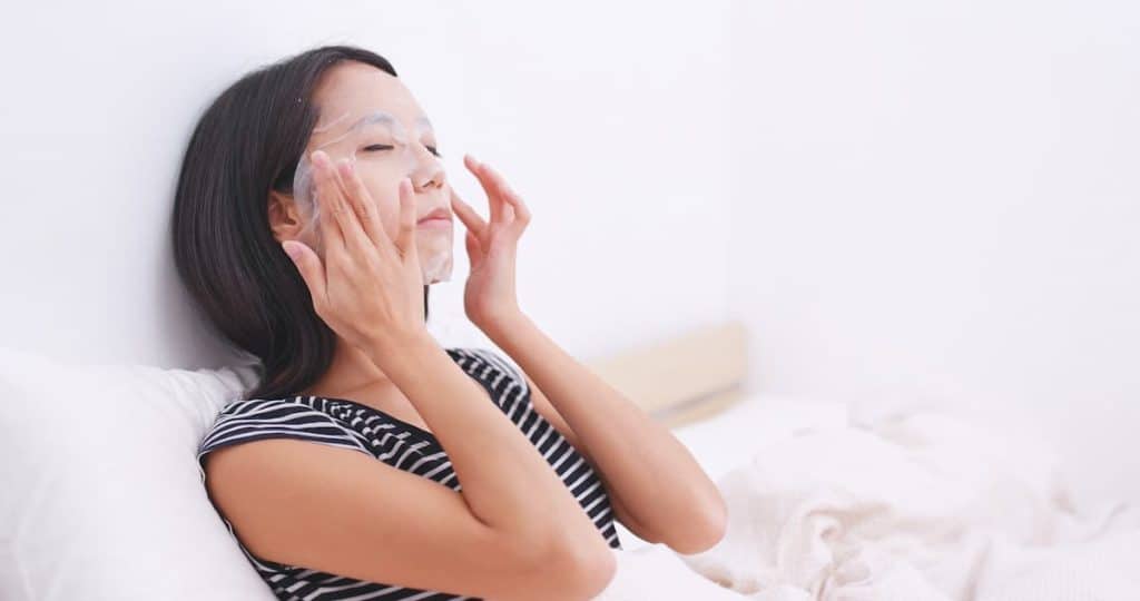short haired woman wearing black and white blouse is applying face mask in bea