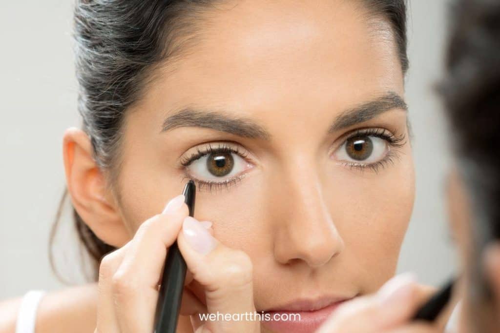 a woman with hooded eyes applying blank eyeliner in her lower line