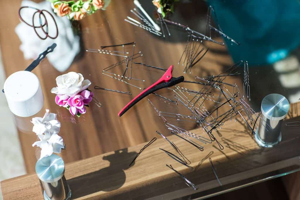 Different sizes and types of hair clips are placed on a wooden and mirrored table