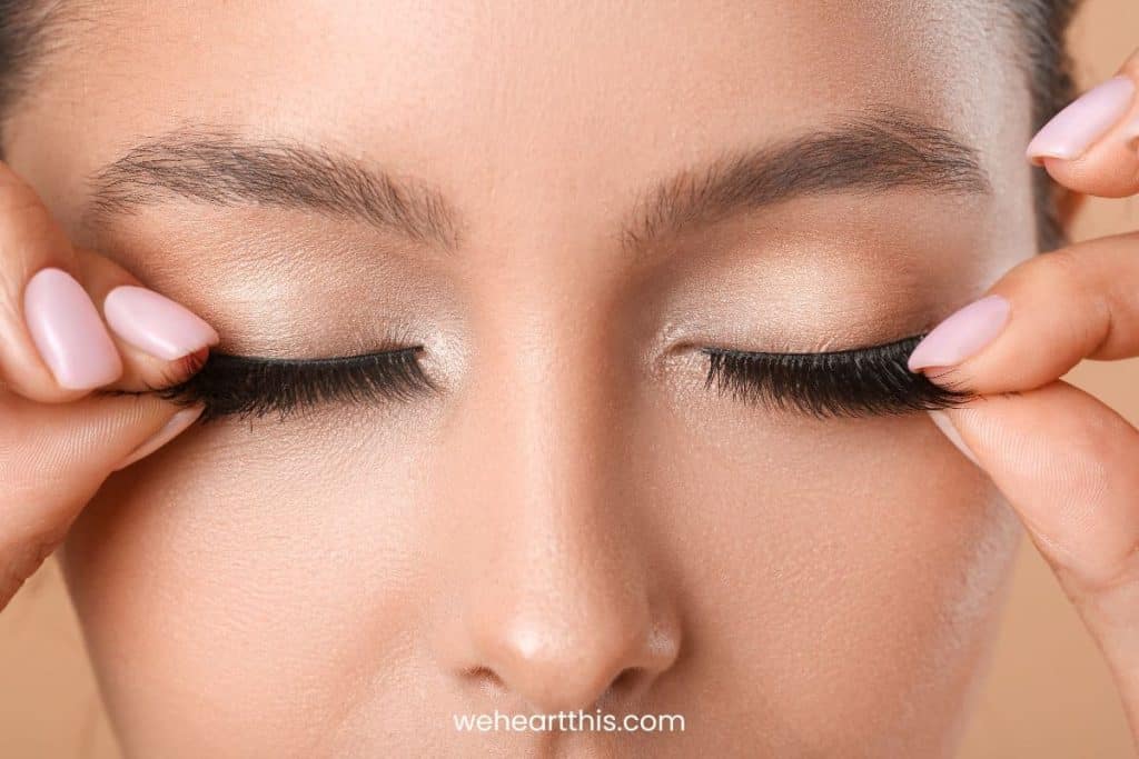 a close-up image of a young girl touching her fake eyelashes