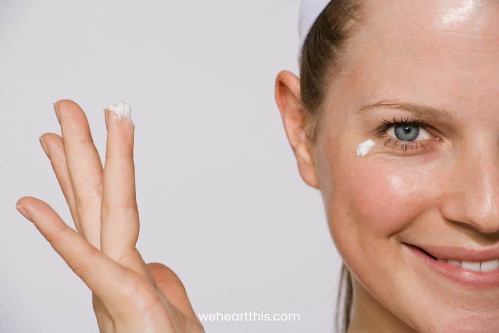 a close-up image of a woman with a dot of snail mucin eye cream on her under eye 