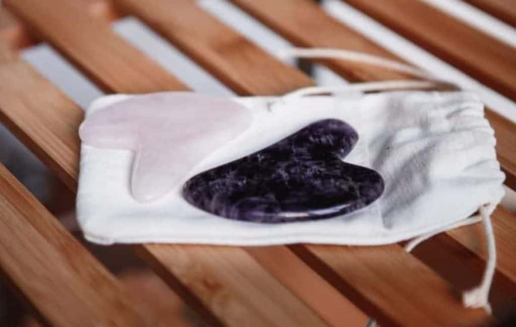 two gua sha laid in a small pouch placed in a wooden chair
