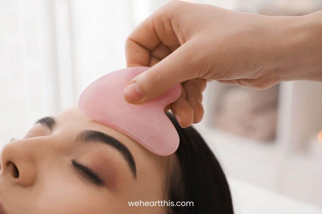 a massage therapists massaging the face of her client using rose quartz gua sha
