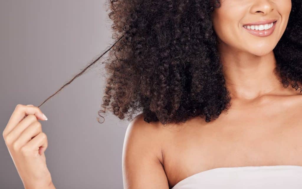 A woman with afro hair is holding her hair.