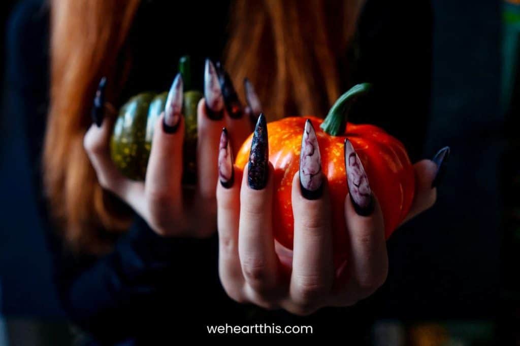 a close-up image of a nightmare before christmas nails with a woman holding a small pumpkin
